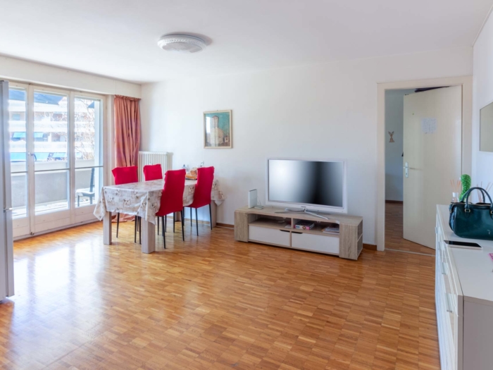 Salle à manger moderne avec table et coin TV – appartement Clarens