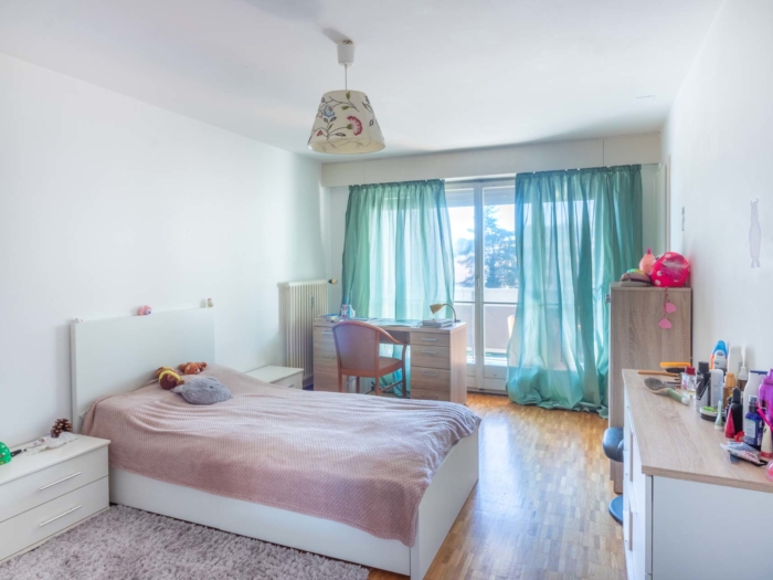 Chambre lumineuse avec parquet et grande fenêtre donnant sur le lac – appartement Clarens
