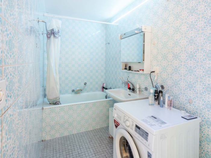 Salle de bain avec baignoire, carrelage rétro et machine à laver – appartement Clarens