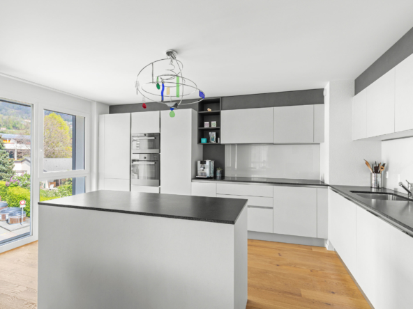Cuisine lumineuse avec îlot central, grandes fenêtres et vue dégagée sur la nature