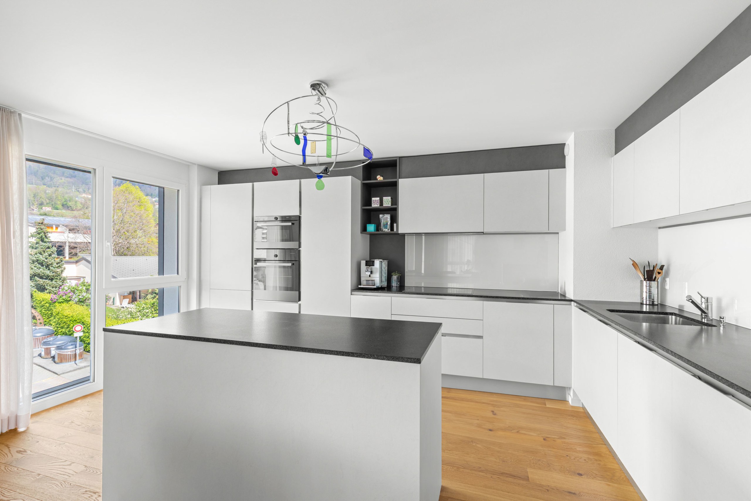Cuisine lumineuse avec îlot central, grandes fenêtres et vue dégagée sur la nature