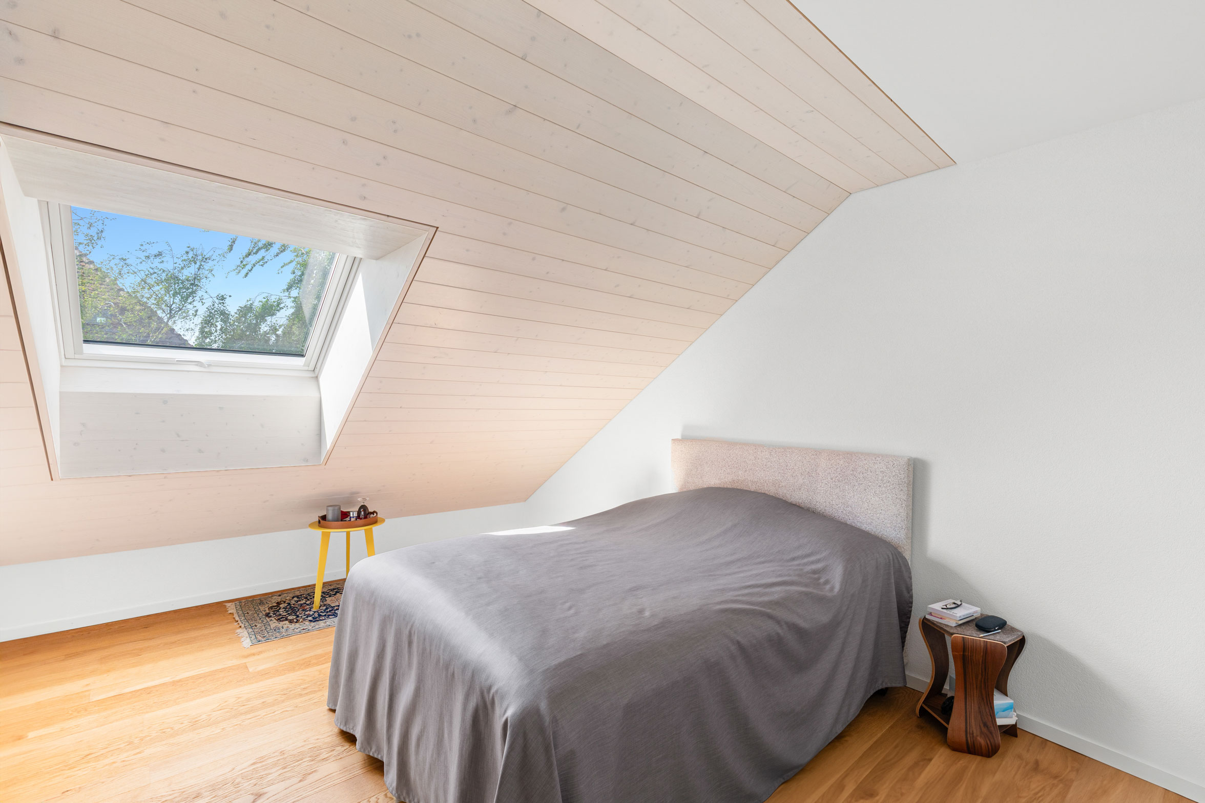 Chambre mansardée avec fenêtre de toit et parquet en bois clair