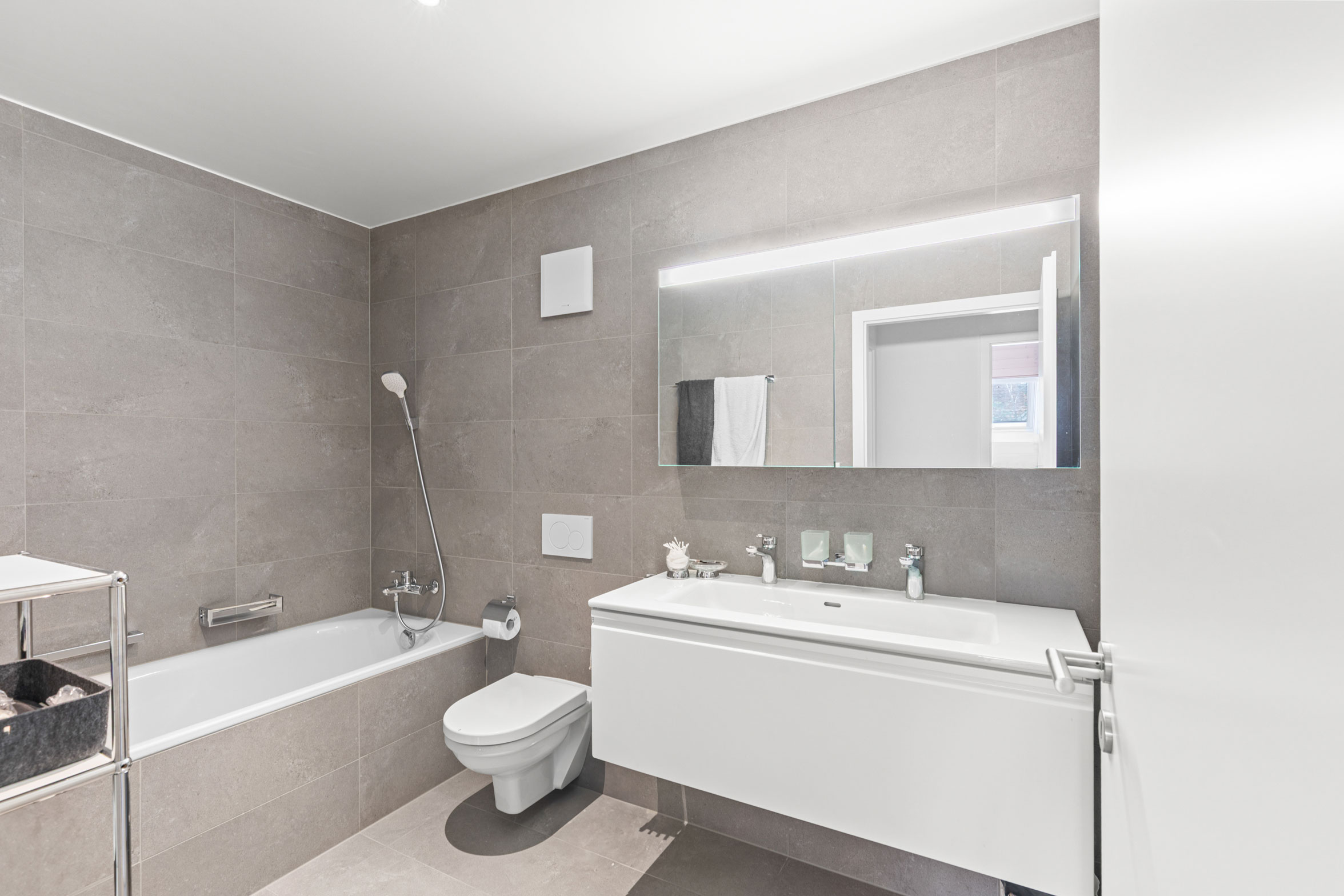 Salle de bain élégante avec baignoire, WC suspendu et meuble vasque avec grand miroir