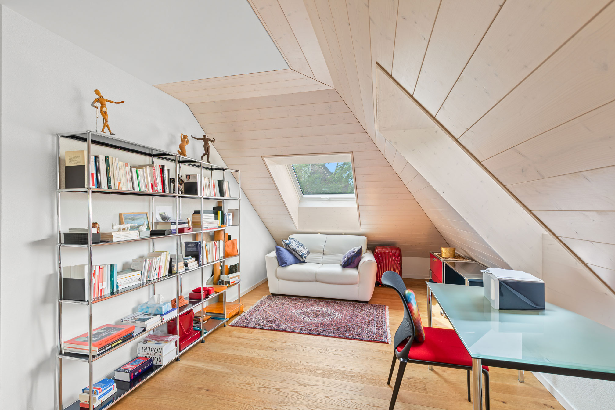 Bureau sous combles avec canapé, bibliothèque et éclairage naturel