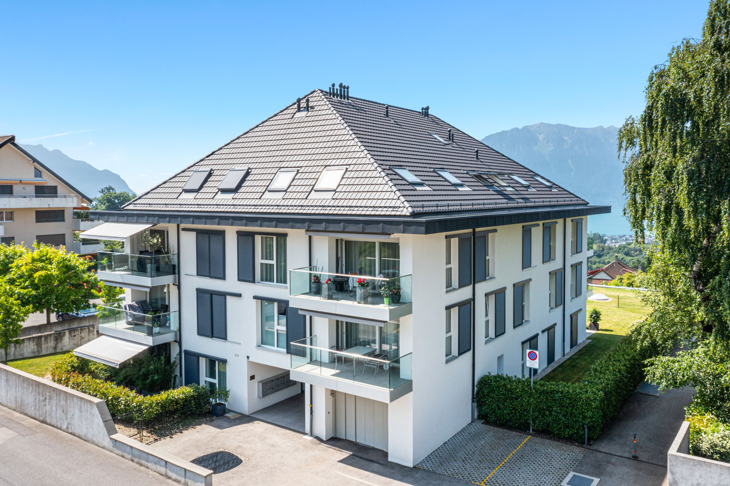 Façade d’un immeuble contemporain avec balcons vitrés et stores solaires