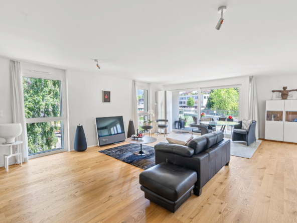 Grand séjour lumineux avec parquet en bois clair, mobilier design et baie vitrée sur balcon