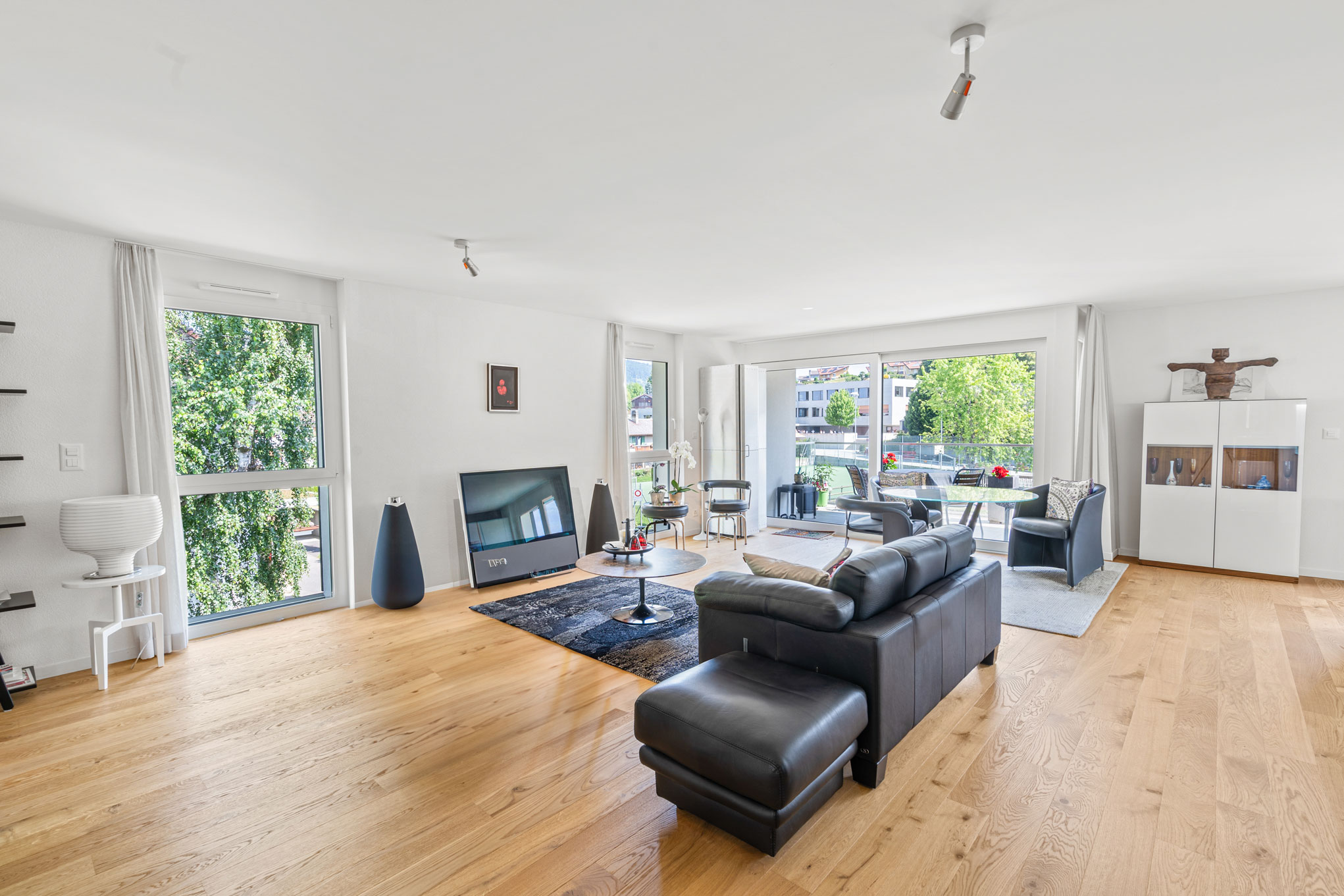 Grand séjour lumineux avec parquet en bois clair, mobilier design et baie vitrée sur balcon
