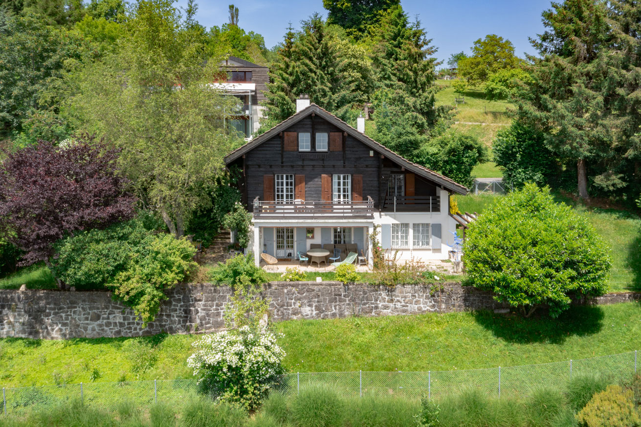 Chalet typique à Jongny entouré de végétation Façade d’un chalet traditionnel entouré de verdure à Jongny, avec terrasse et volets en bois