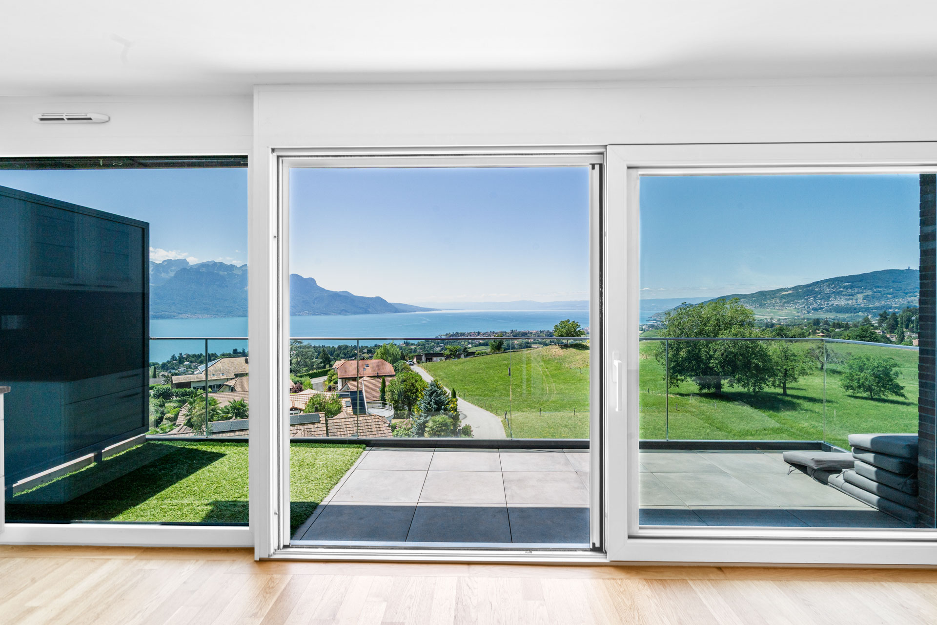 Vue sur terrasse et baies vitrées avec panorama sur le lac Léman et les montagnes