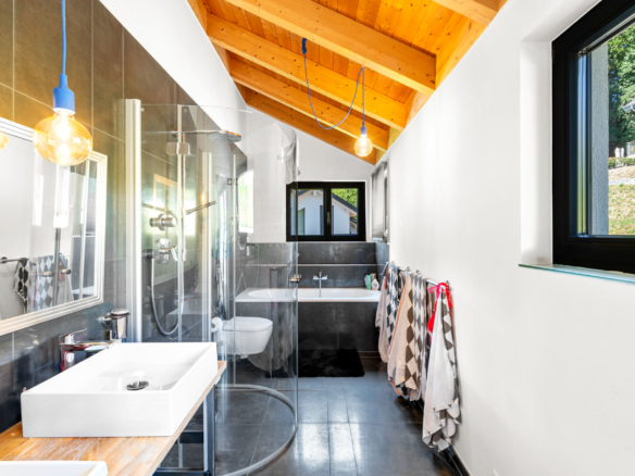 Salle de bains secondaire avec douche, baignoire et double vasque sous toit en pente à St-Légier