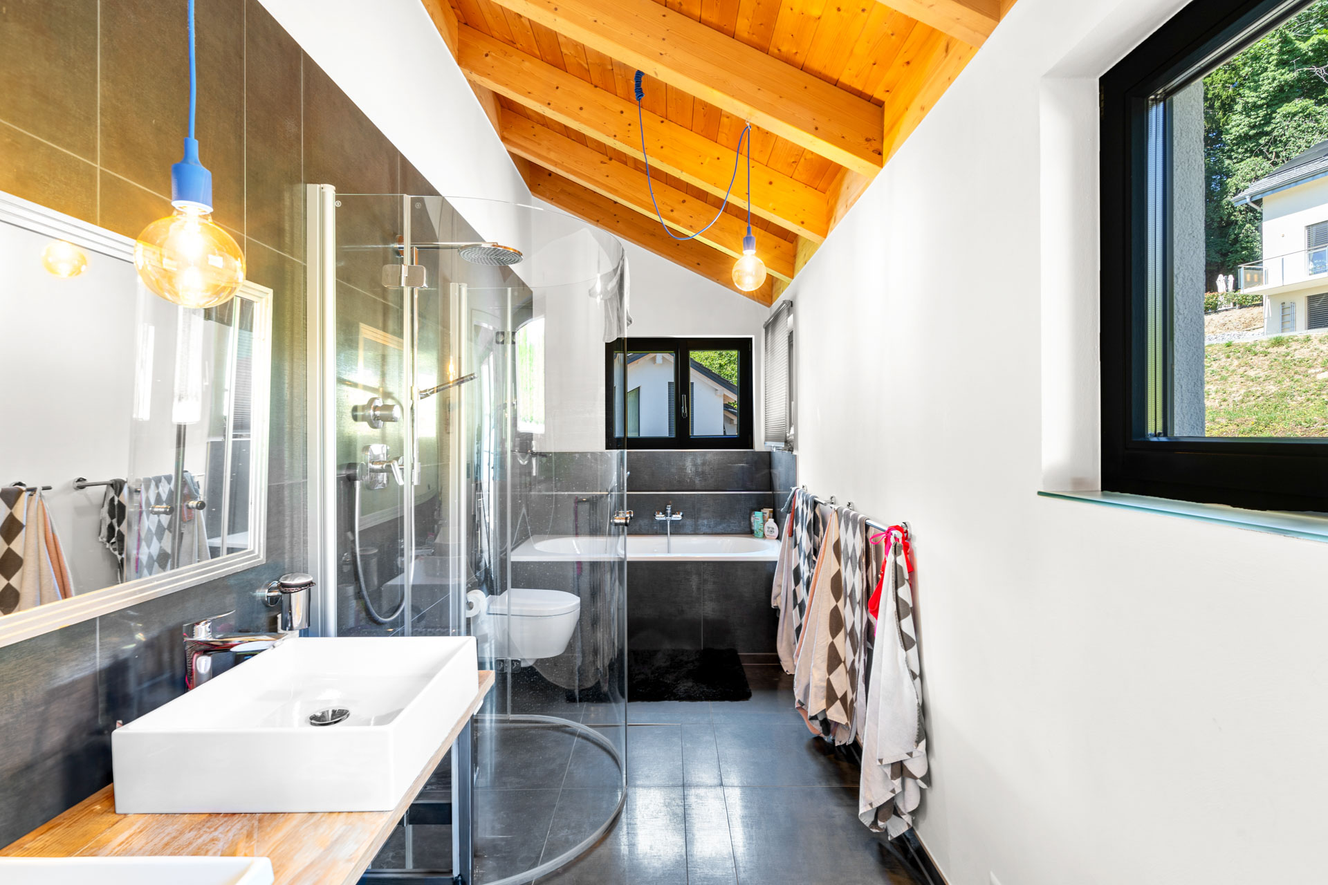 Salle de bains secondaire avec douche, baignoire et double vasque sous toit en pente à St-Légier