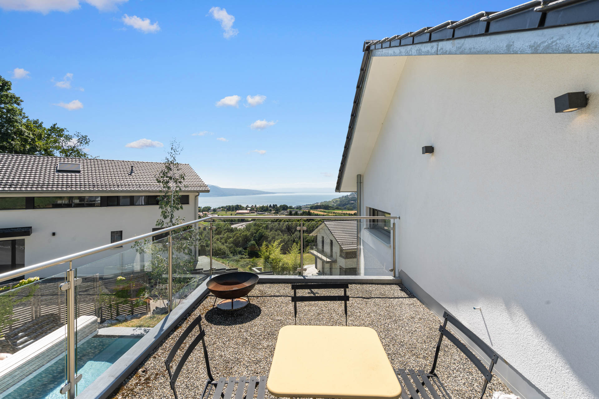 Terrasse en gravier avec mobilier extérieur et vue panoramique sur le lac à St-Légier