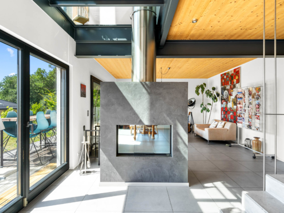 Poêle moderne à double face avec habillage en béton ciré, séparant salon et salle à manger à St-Légier