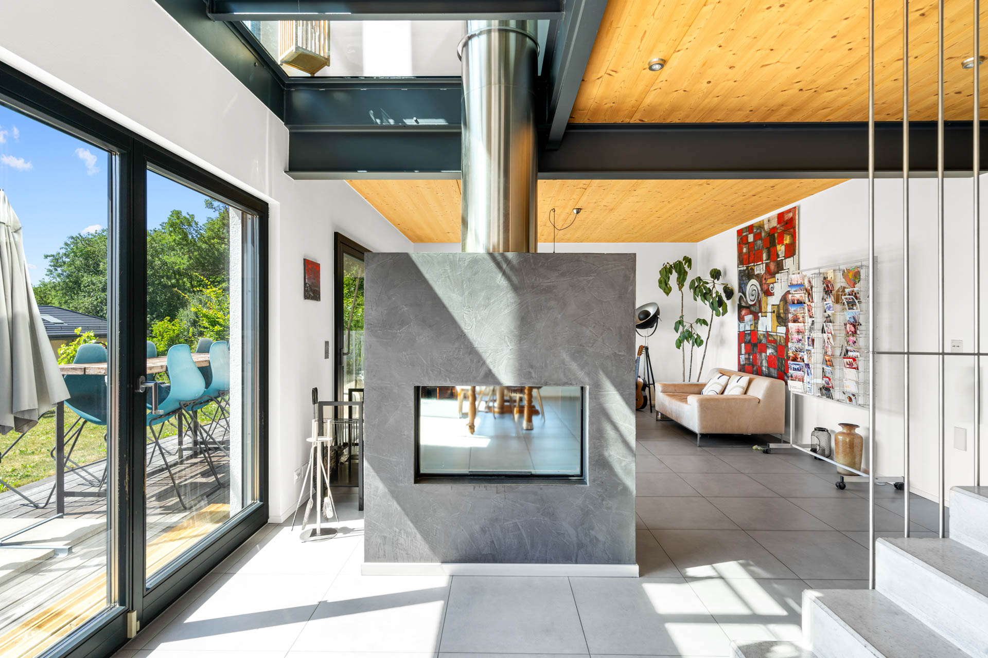 Poêle moderne à double face avec habillage en béton ciré, séparant salon et salle à manger à St-Légier