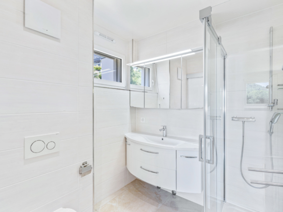 Salle de bains moderne avec douche vitrée, carrelage clair et meuble vasque contemporain