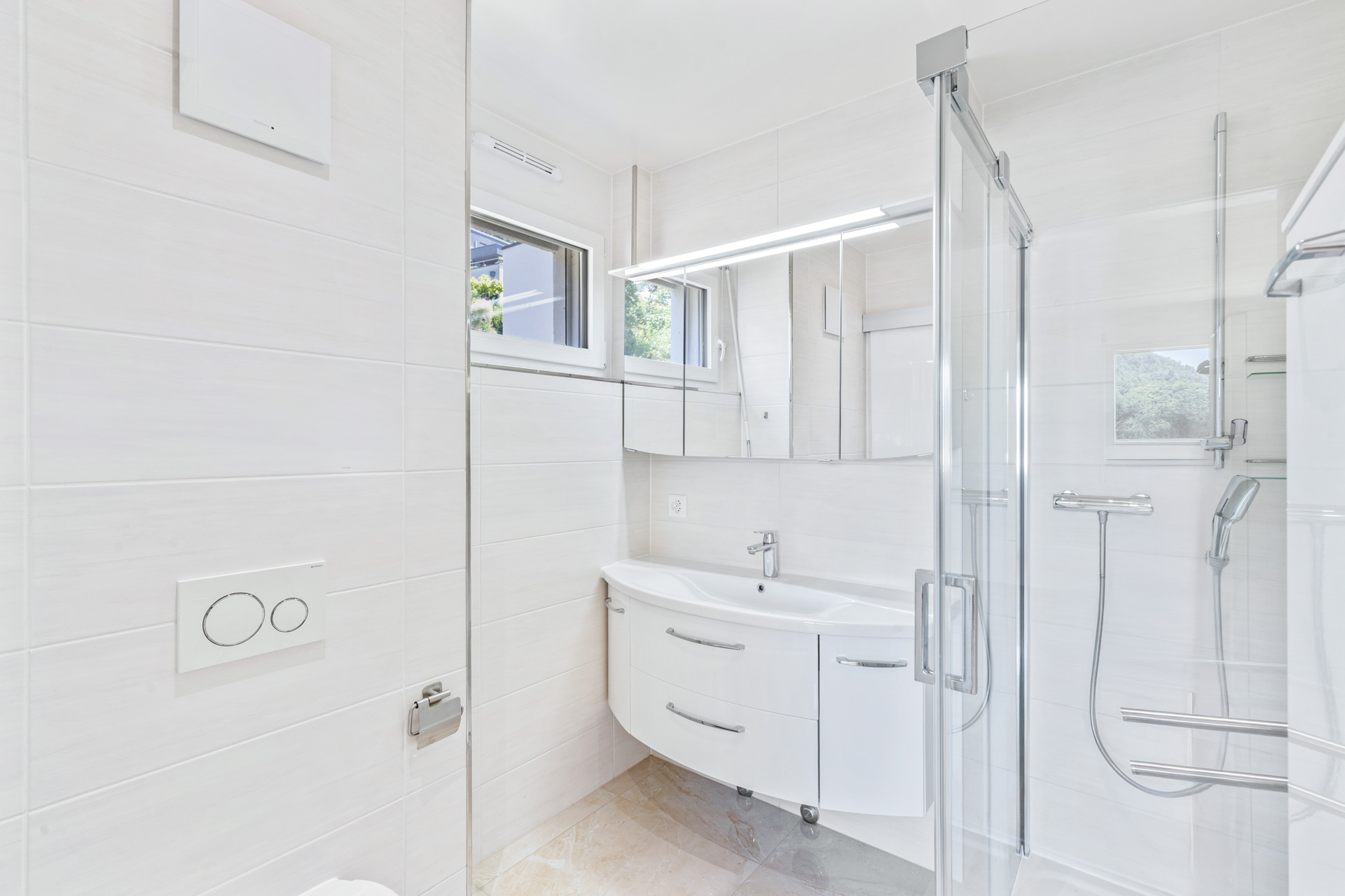 Salle de bains moderne avec douche vitrée, carrelage clair et meuble vasque contemporain