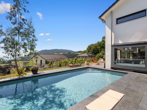 Piscine extérieure avec margelles sombres et vue sur le lac et les montagnes à St-Légier