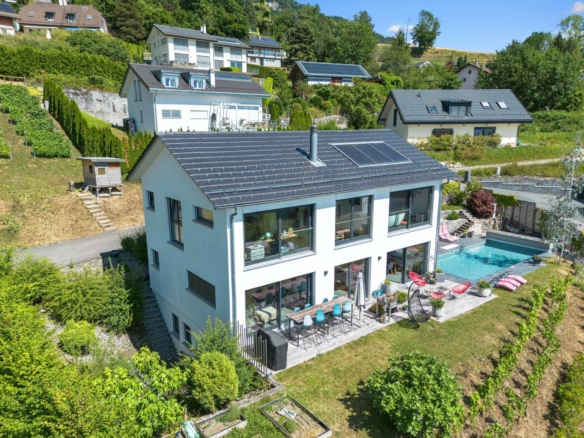 Vue extérieure de la maison moderne avec piscine et terrasses, entourée de verdure à St-Légier