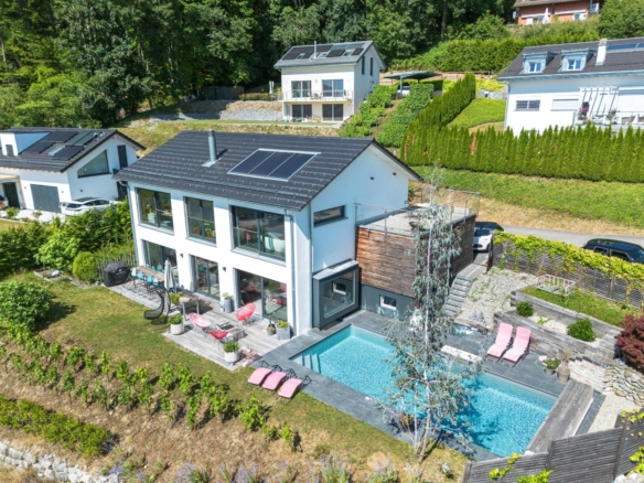 Vue oblique sur la maison, ses terrasses, la piscine et le jardin paysager à St-Légier