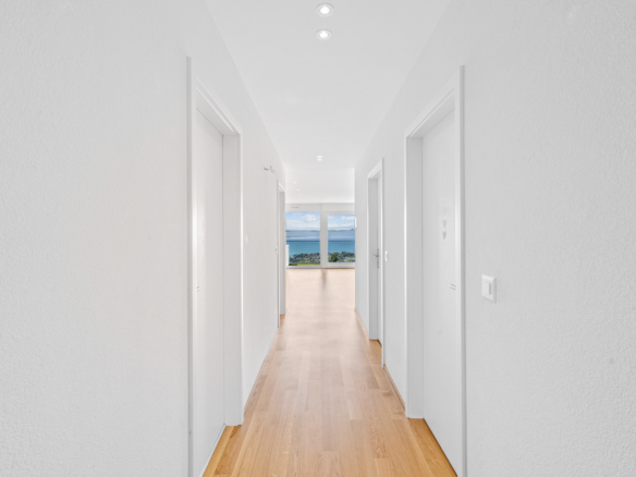Couloir intérieur avec parquet et accès sur séjour avec vue lac