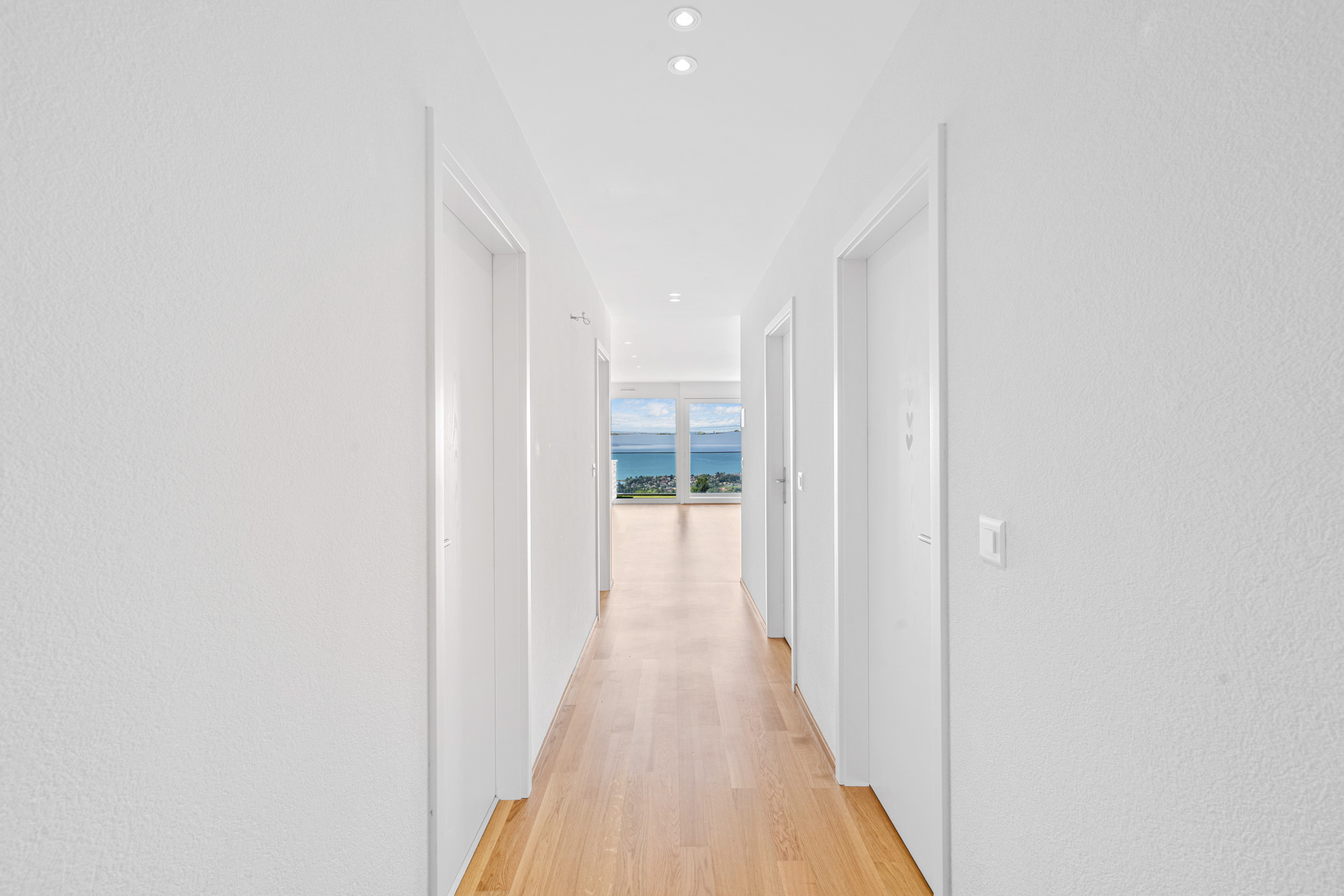 Couloir intérieur avec parquet et accès sur séjour avec vue lac