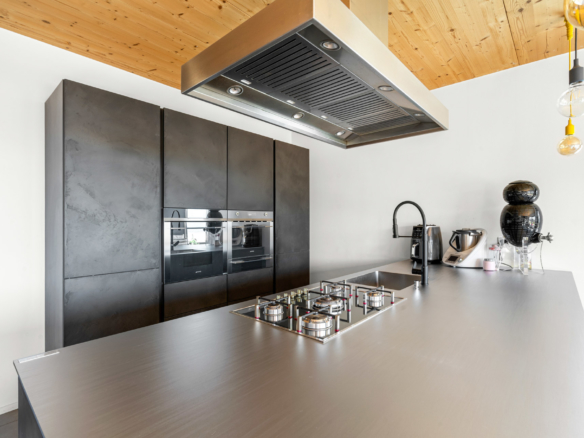 Cuisine haut de gamme avec îlot central, plaques de cuisson gaz et hotte inox à St-Légier