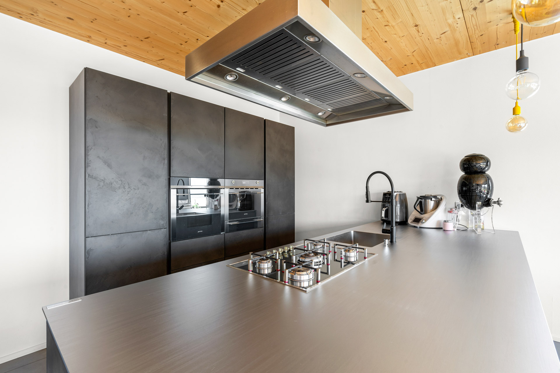 Cuisine haut de gamme avec îlot central, plaques de cuisson gaz et hotte inox à St-Légier