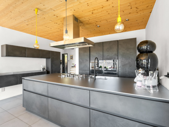 Vue d’ensemble de la cuisine avec rangements muraux et éclairage suspendu coloré à St-Légier