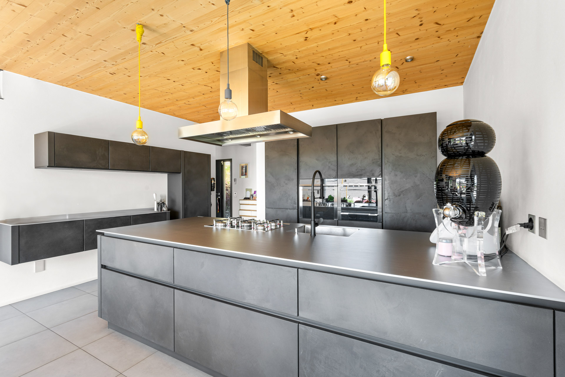 Vue d’ensemble de la cuisine avec rangements muraux et éclairage suspendu coloré à St-Légier