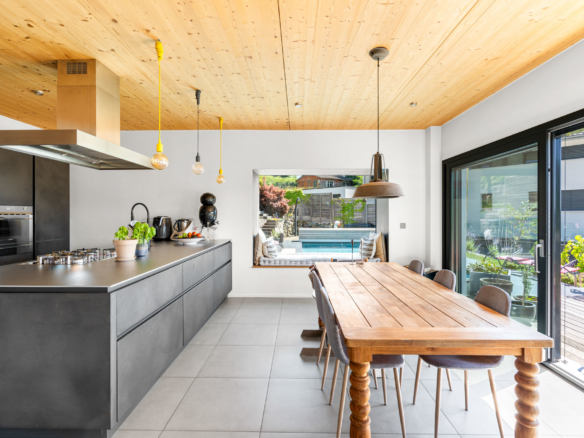 Coin salle à manger avec grande table en bois massif et vue sur la piscine extérieure à St-Légier