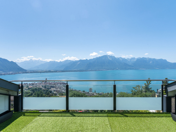 Vue panoramique sur le lac Léman et les montagnes depuis une terrasse avec gazon synthétique à Chernex