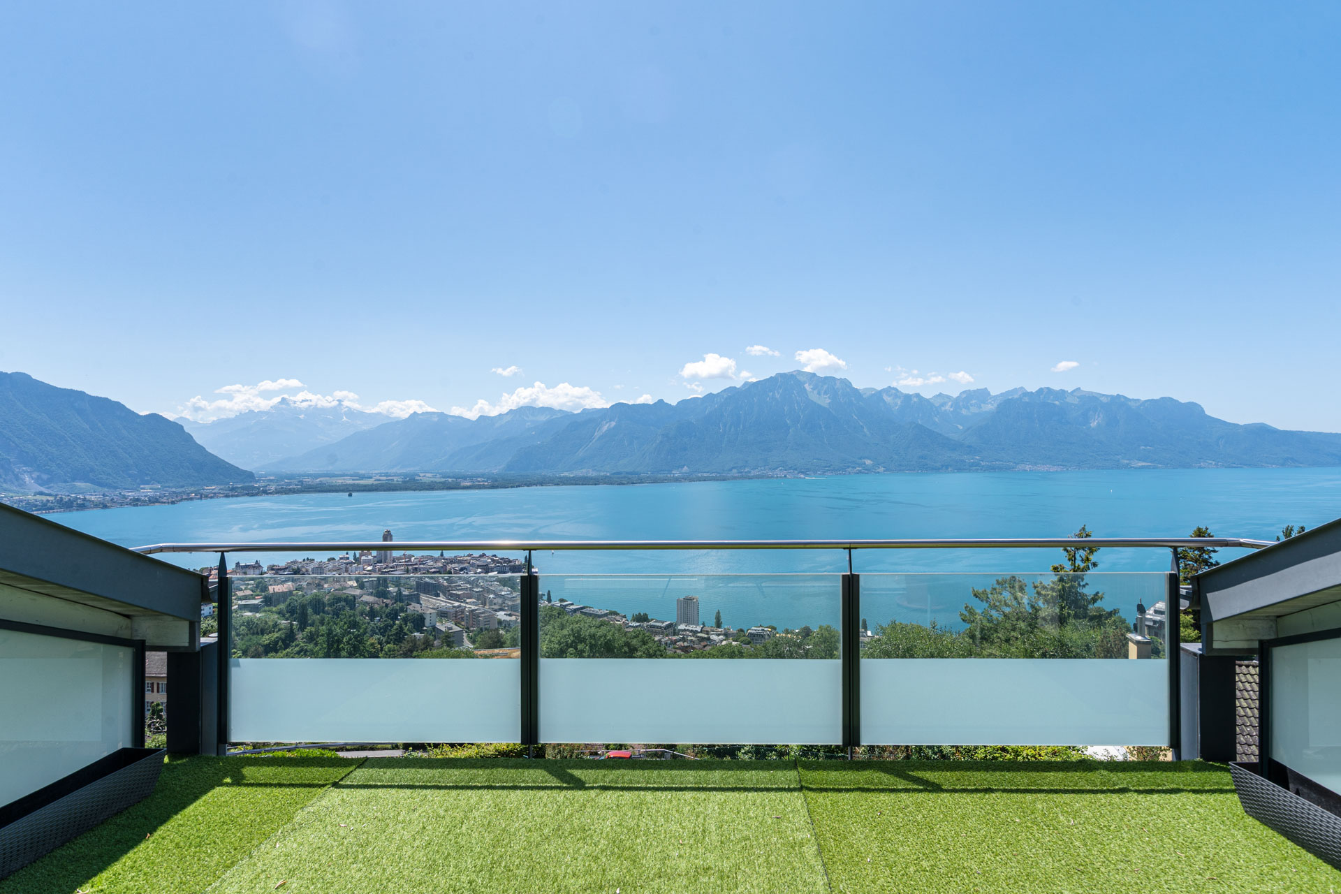 Vue panoramique sur le lac Léman et les montagnes depuis une terrasse avec gazon synthétique à Chernex