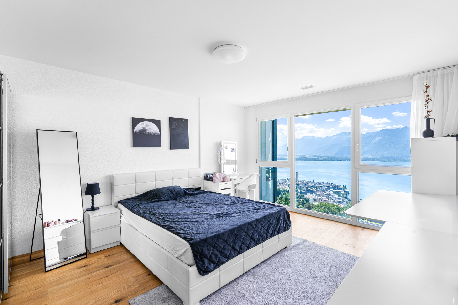 Chambre avec lit double, mobilier blanc et grande baie vitrée offrant une vue sur le Léman à Chernex