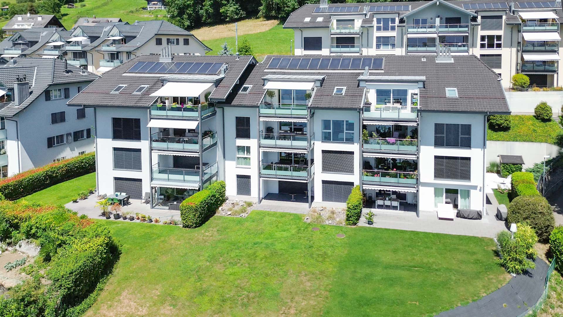Façade arrière d’un immeuble résidentiel avec terrasses et espaces verts à Chernex