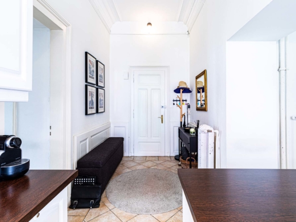 Entrée aménagée avec banc et porte blanche dans appartement de Territet