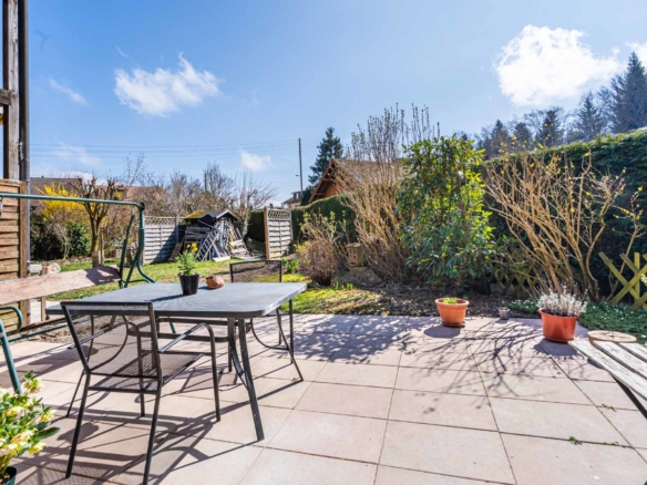 Terrasse aménagée avec salon de jardin et haies naturelles