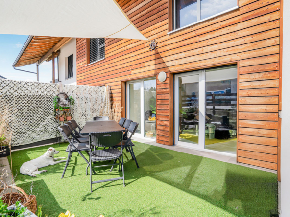 Terrasse privative à Bournens avec table à manger extérieure et gazon synthétique