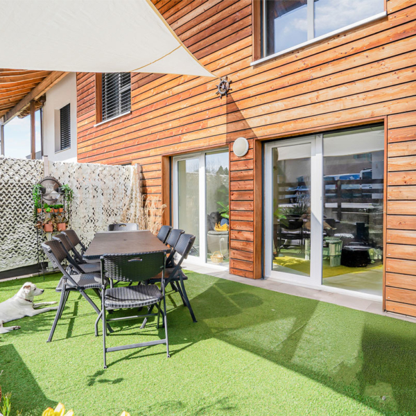 Terrasse privative à Bournens avec table à manger extérieure et gazon synthétique