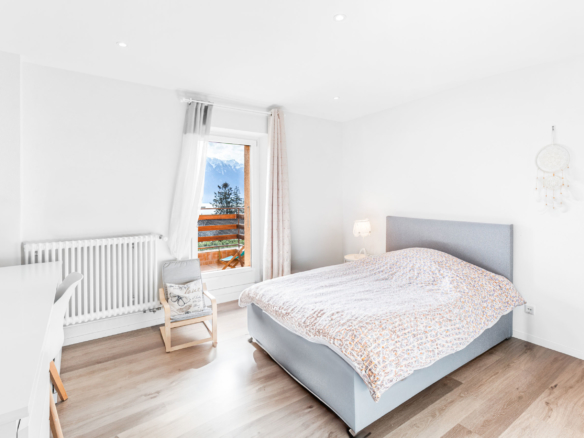 Chambre lumineuse avec accès balcon, lit double et vue dégagée sur les montagnes.
