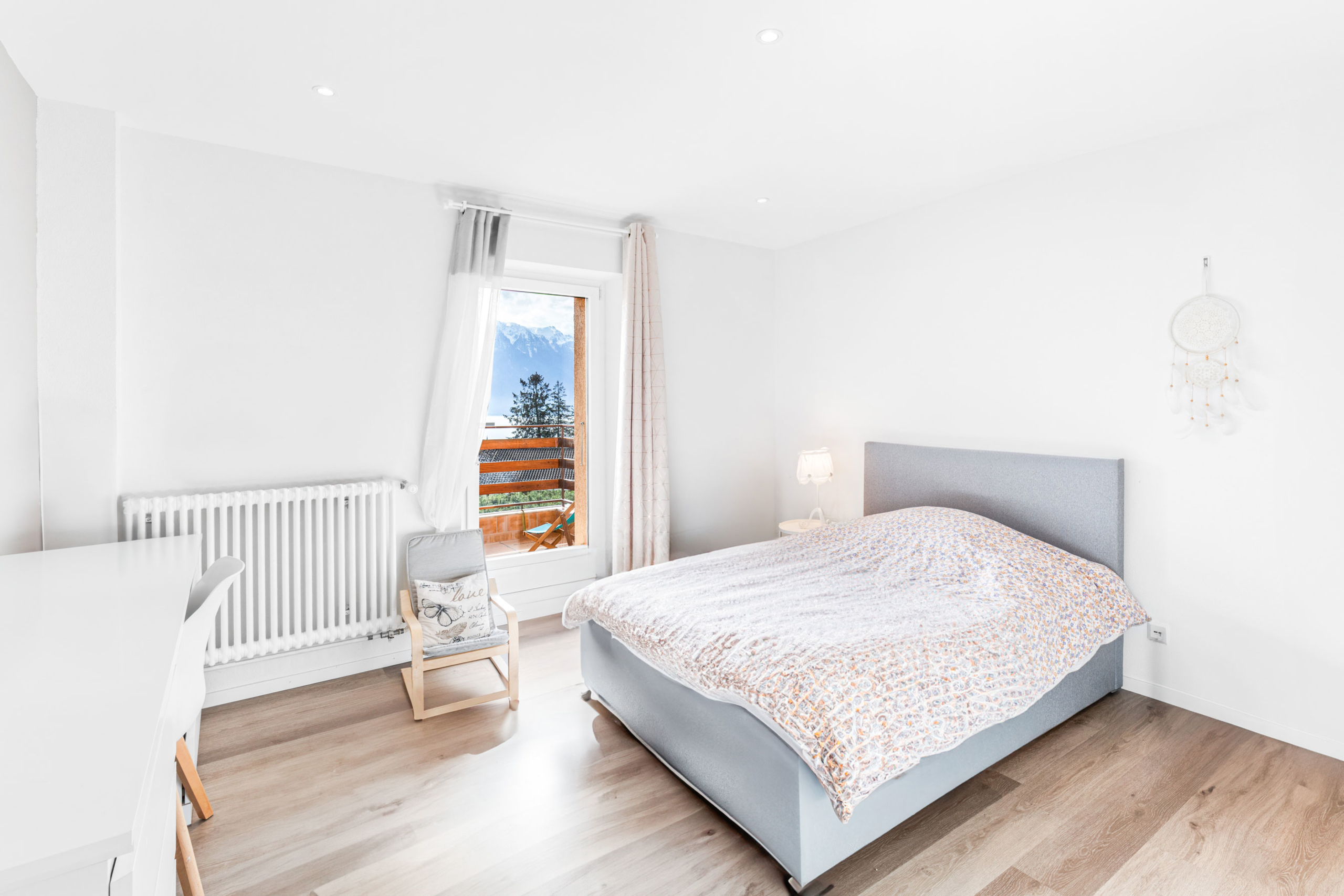 Chambre lumineuse avec accès balcon, lit double et vue dégagée sur les montagnes.