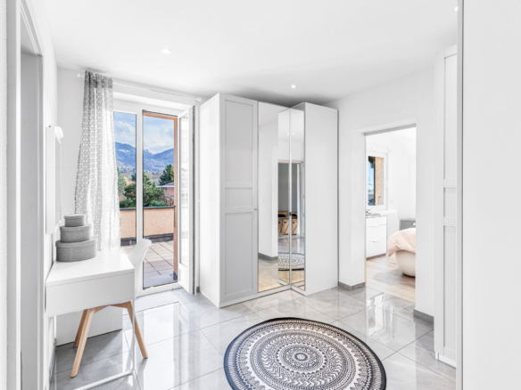 Hall d’entrée lumineux avec grands rangements et accès à une terrasse extérieure avec vue montagne.