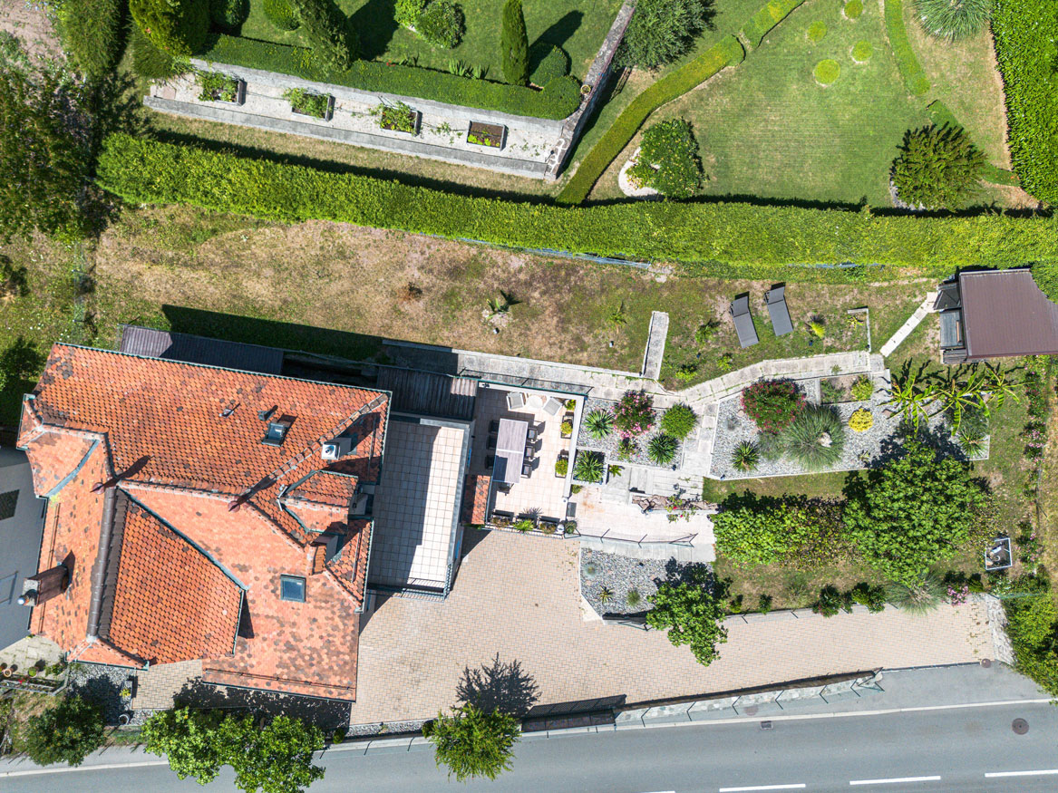 Vue aérienne de la propriété et de son jardin paysagé, terrasse, allées en pierre et espace détente.