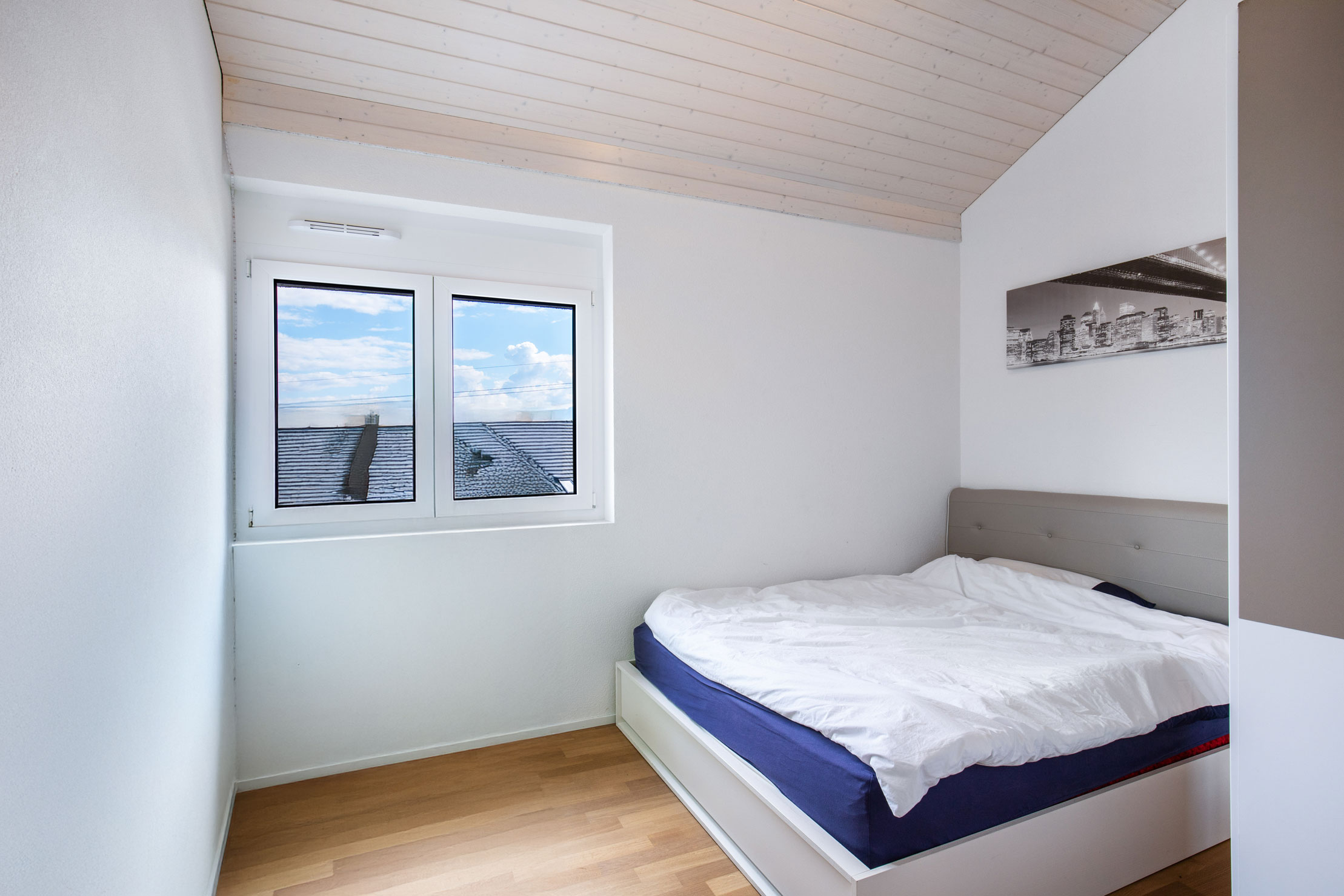 Chambre fonctionnelle avec coin bureau, lit double et vue dégagée sur le lac Léman à Jongny.