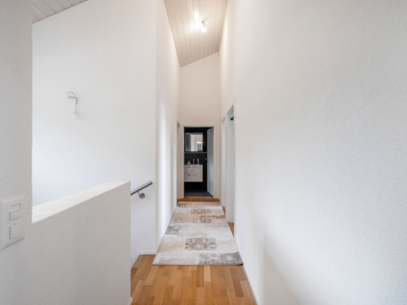 Couloir à l’étage avec plafond haut lambrissé menant aux chambres et à la salle de bain à Jongny.