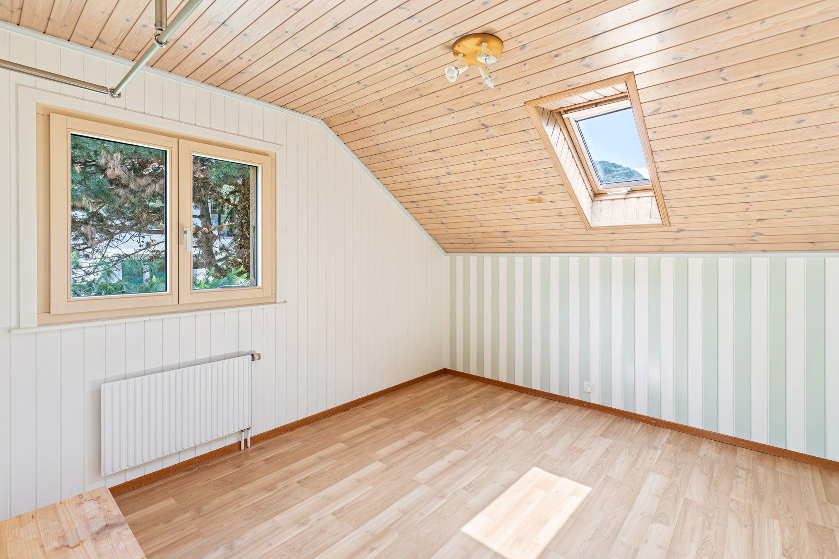 Chambre sous combles avec lambris au plafond, mur à rayures verticales et parquet clair