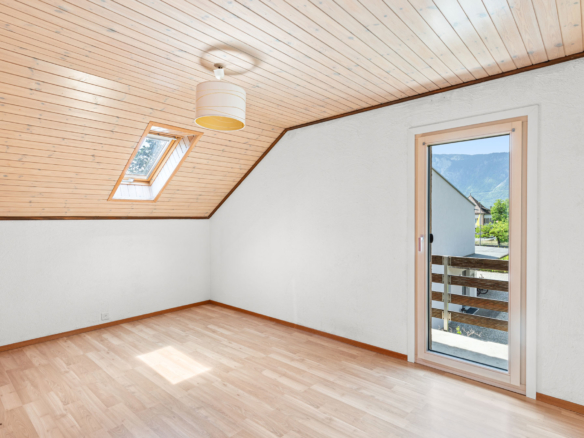 Chambre avec fenêtre de toit, parquet clair et accès balcon avec vue