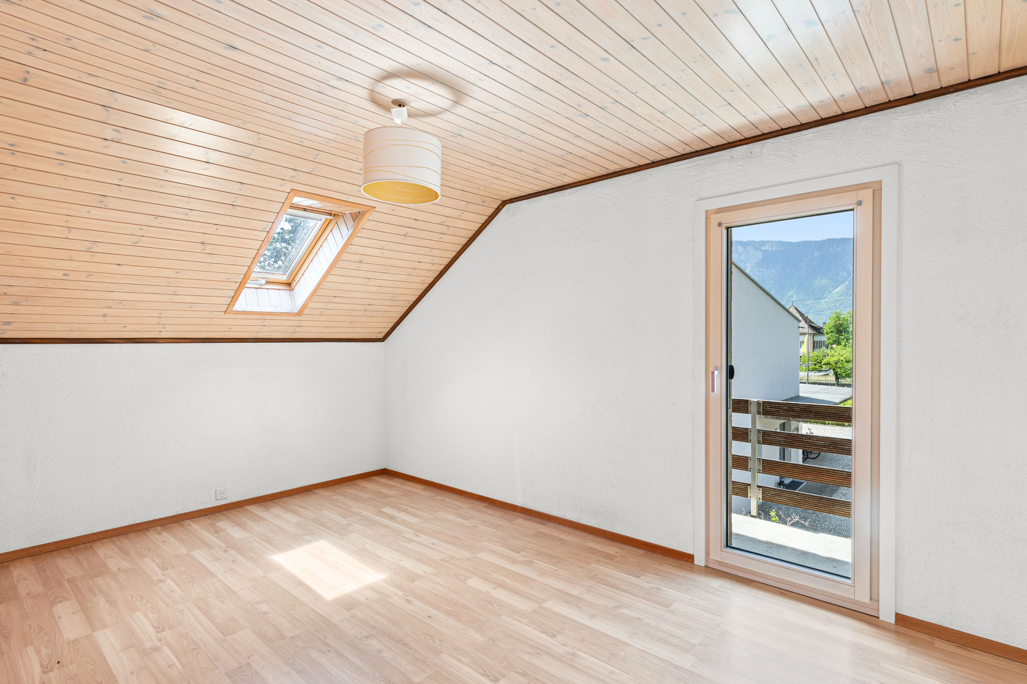 Chambre avec fenêtre de toit, parquet clair et accès balcon avec vue