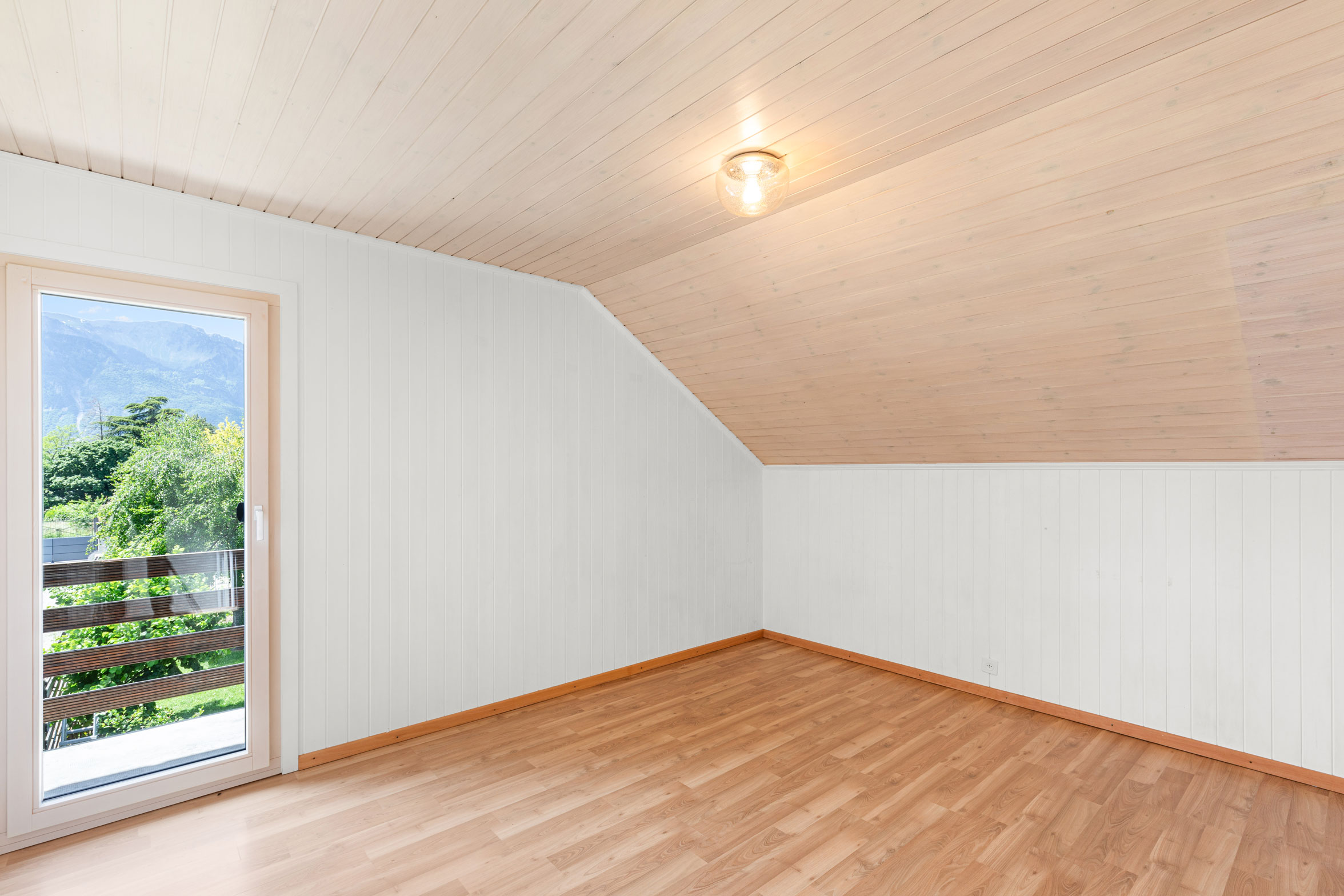Chambre avec balcon et lambris clair sur les murs et plafond