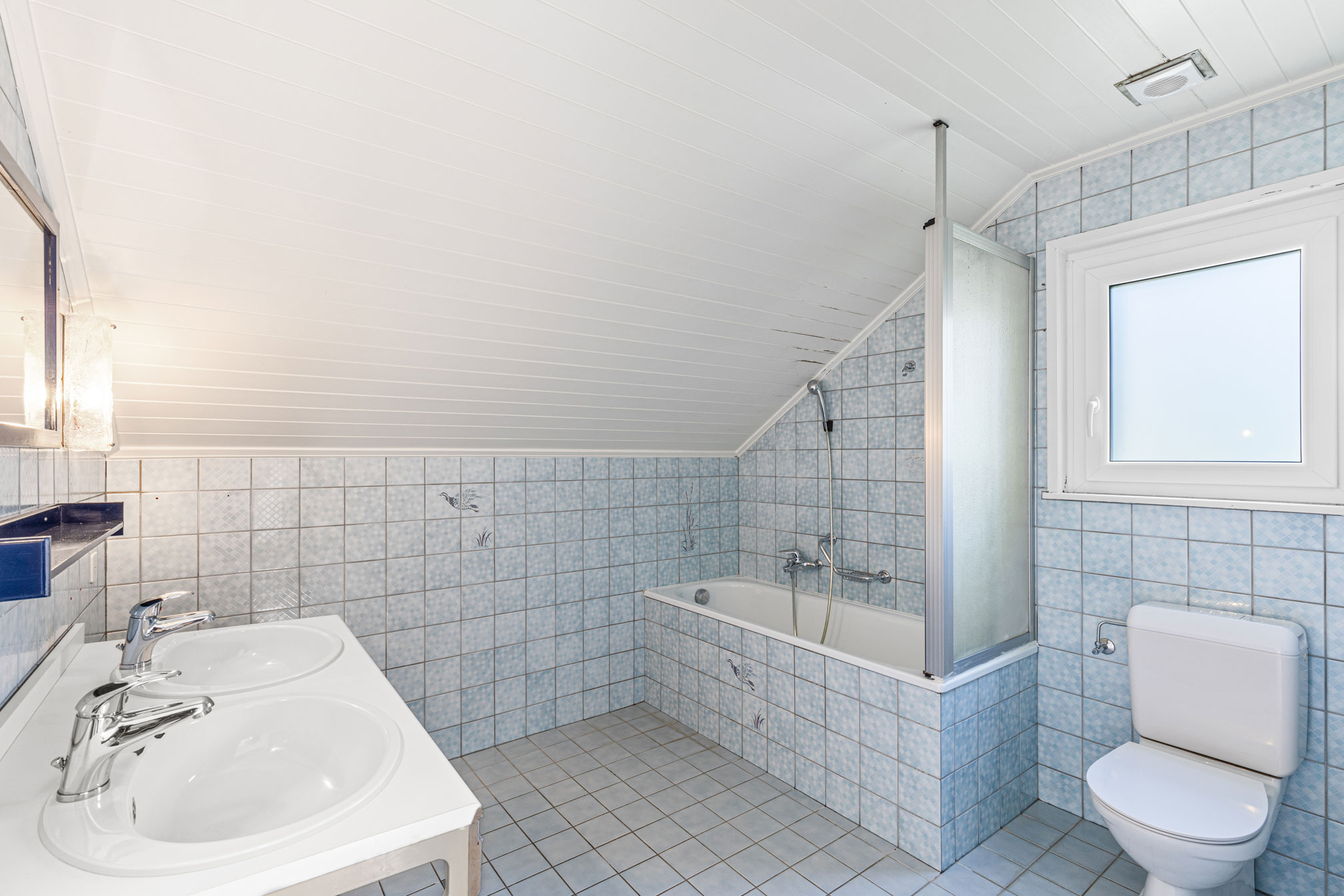 Salle de bain avec baignoire, carrelage bleu et double vasque