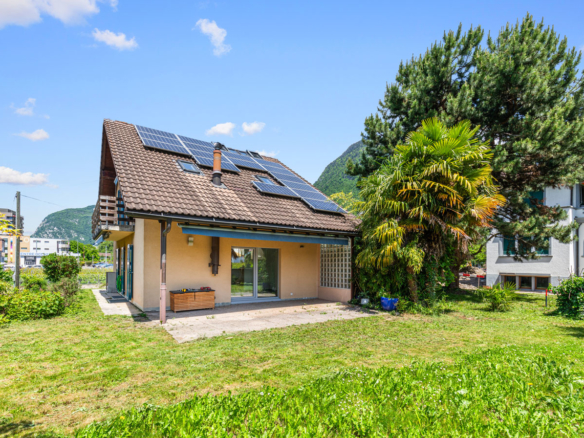 Maison individuelle avec panneaux solaires, toit en pente et jardin verdoyant